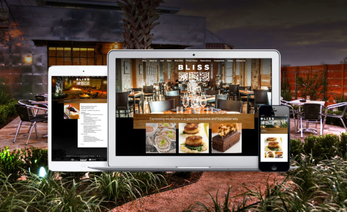 Bliss-Bliss Restaurant website displayed on multiple devices, showcasing a cozy fine dining ambiance with elegant table settings, delicious food images, and a scenic outdoor seating area