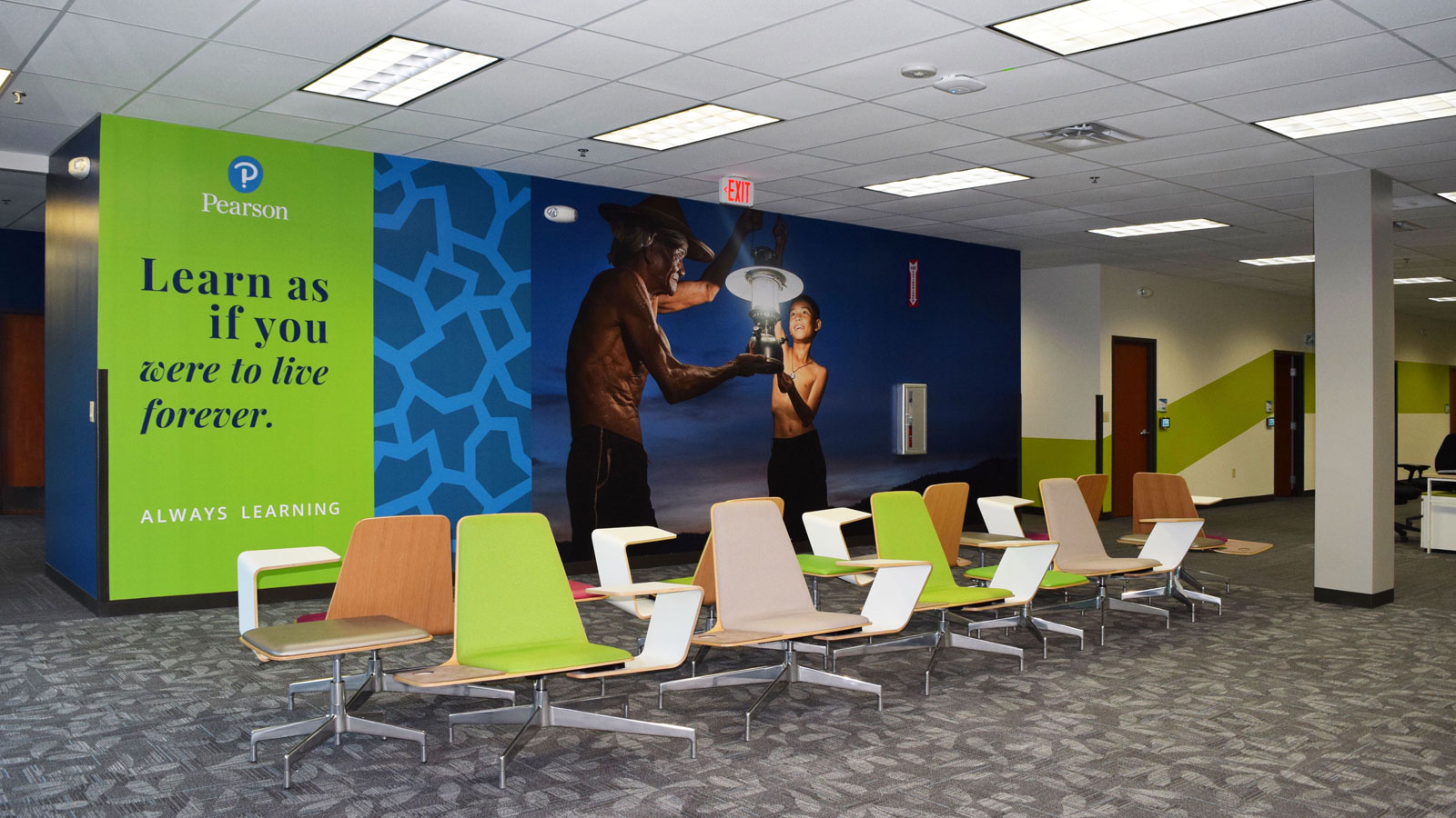 Pearson – Austin - Pearson learning space featuring inspirational quote ‘Learn as if you were to live forever,’ modern seating, and vibrant wall design.