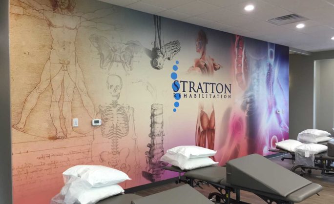 Stratton - Stratton Rehabilitation clinic interior with anatomical illustrations and the clinic’s logo on a feature wall.