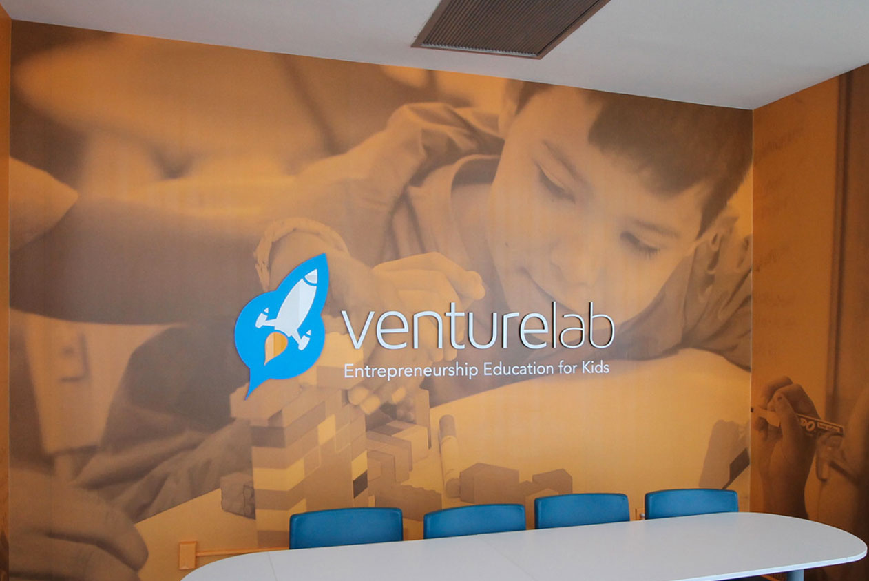 Venture Lab - A wall mural featuring a photo of a child building with blocks. The VentureLab logo and tagline "Entrepreneurship Education for Kids" are prominently displayed.