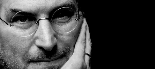 Steve Jobs - Close-up black-and-white portrait of a man wearing glasses, resting his face on his hand, looking thoughtful