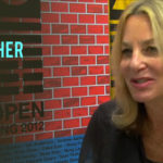 Paula Scher speaking at the AGI Open event, featuring vibrant, colorful design elements in the background.