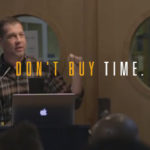 Speaker presenting at a seminar with the text overlay ‘Don’t Buy Time’ emphasizing a motivational message.