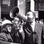 Martin Luther King Jr. speaks passionately through a megaphone during a civil rights protest.