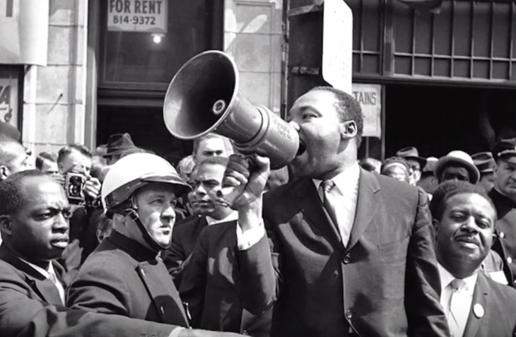 Martin Luther King Jr. speaks passionately through a megaphone during a civil rights protest.