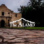 The Vault: The Alamo -Our Work - This is an image of the iconic Alamo, featuring its historic stone facade, with "The Alamo" logo prominently displayed. The setting highlights the paved courtyard and surrounding greenery, emphasizing the landmark's cultural and historical significance.