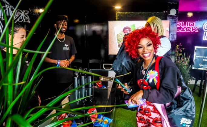 a woman with red hair standing in front of a table with people behind her