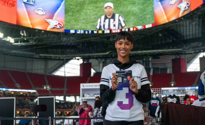 a woman holding a card in front of a large screen