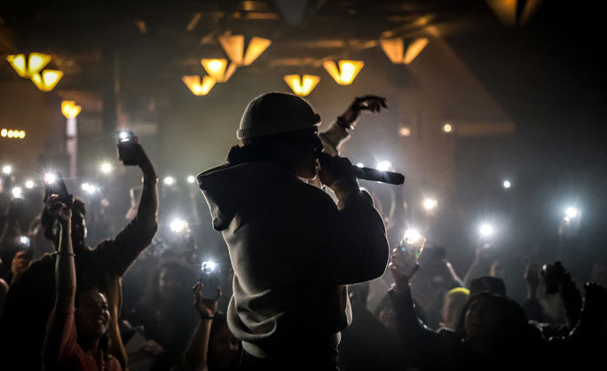 a person singing into a microphone with a crowd of people in the background